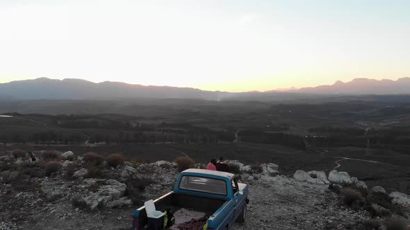 Young couple on a road trip sitting outside on their truck at dusk