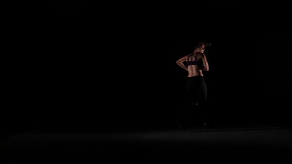 Young Girl Jumps Dancing Contemp in the Shadow on Black Background, Slow Motion