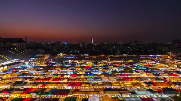 day to night time lapse of Train Night Market Ratchada (Talad Rot Fai) at night in Bangkok, Thailand