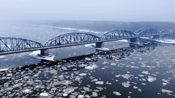 Snowy bridge and river with floe in winter.