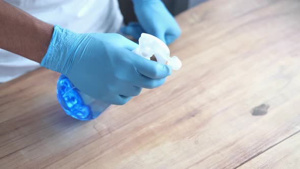 Hand in Blue Rubber Gloves Holding Spray Cleaning Flat Surface