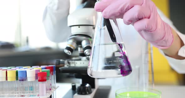 Scientist in Laboratory Holds Volumetric Flask with Purple Chemical