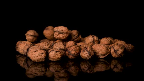 Walnuts Falling Into a Pile of More Walnuts, Black Background