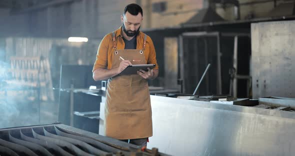 Factory Worker with Tablet and Phone at the Manufacturing