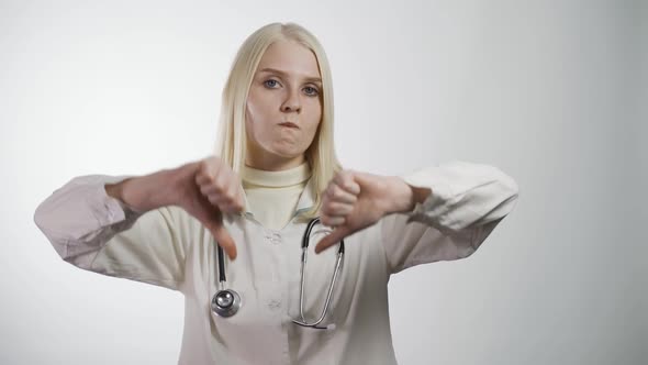 Disappointed Adult Female Doctor Doing a Thumbs Down Sign Studio Isolated Shot Against White