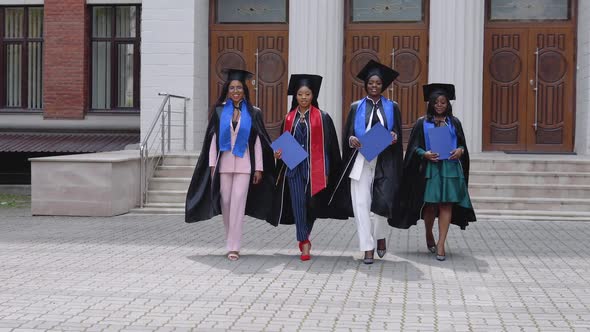 Happy Graduates of a University or College of African American Nationality with Blue Diplomas in