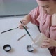 Female Potter Sitting and Stirs Paint with a Brush a Cup on the Table. Woman Making Ceramic Item - VideoHive Item for Sale