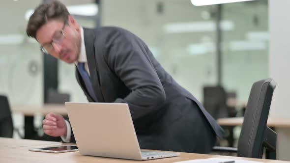 Middle Aged Businessman Coming Back and Starting Work on Laptop in Office 