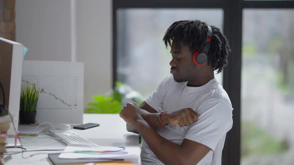 Joyful African American Man Enjoying Music in Headphones Sitting at Computer Table in Home Office