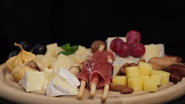 Preparation of cheese plate: parmesan, grapes, honey, nuts, grissini, jamon, prosciutto