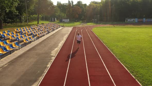 The man training jogging at the stadium in summer