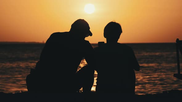 Silhouette Couple of MiddleAged Man and Woman at Sunset on the Beach By Ocean