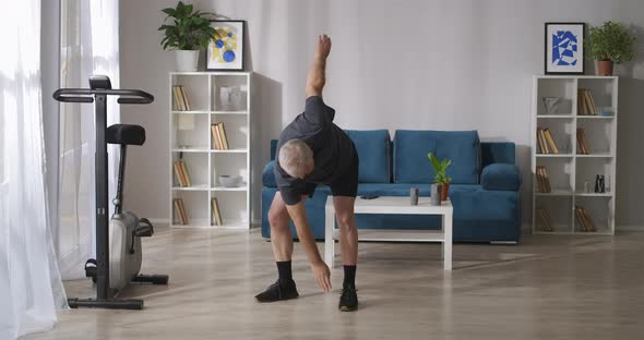 Middleaged Man Is Training Home at Morning Tilts and Stretching Exercises Gymnastics for Joints