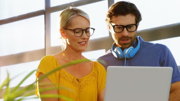 Business executives discussing over laptop