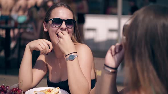 Two Young Attractive Girls Wearing Sunglasses Are Sitting at Table