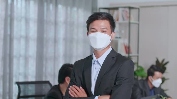 Portrait Of Young Asian Business Man Wearing Face Mask While Standing With Folded Arms At Office