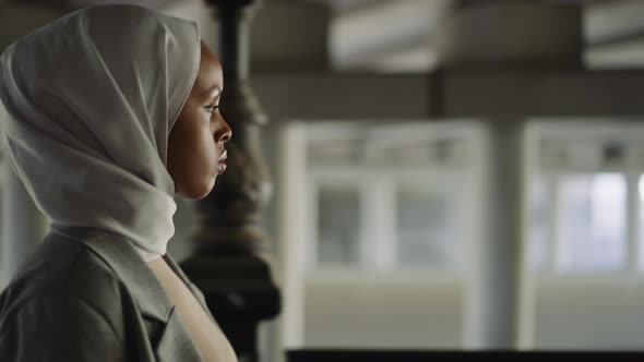 Melancholic Black Woman with Hijab Walks Along Embankment