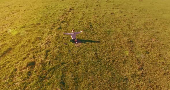 Low Orbital Flight Around Man on Green Grass with Notebook Pad at Yellow Rural Field.