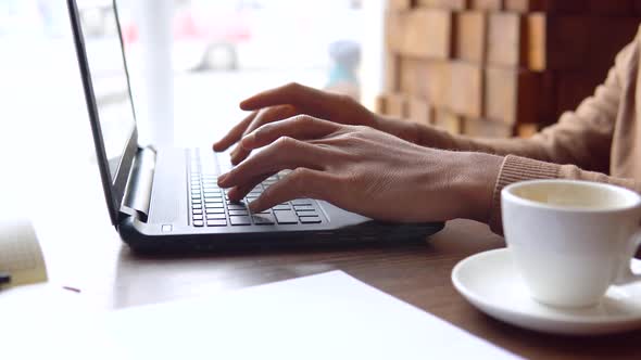 An African American Man with a Serious Expression Works with a Laptop and Documents at Home