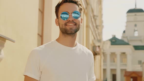 Portrait of handsome stylish hipster man posing outdoors at summer sunny day