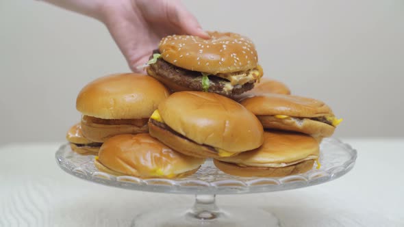 Hands Place Cheeseburgers on a Round Glass Dish