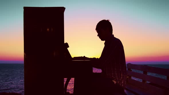 Young Man Playing Melody on Piano on Seashore