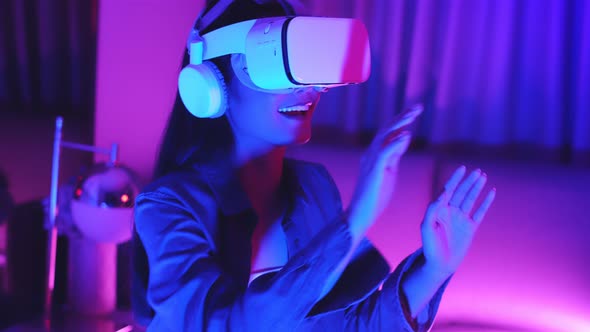Young asian woman is using virtual reality headset. Neon light studio portrait.