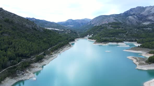 Wide Aerial Pushout of Lake and Forested Hills in Guadalest Spain
