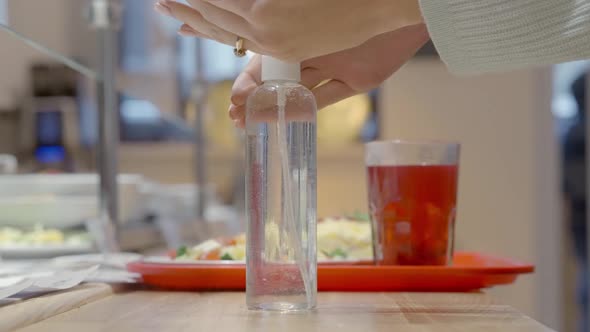 Closeup of Unrecognizable Woman Disinfecting Hands with Sanitizer in Selfservice Restaurant Taking