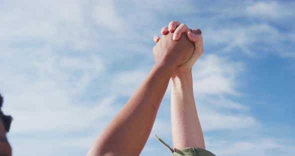 Midsection of diverse female gay couple raising and holding hands