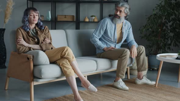 Man and Woman Sitting on Couch with Angry Faces Sighing Expressing Negative Emotions