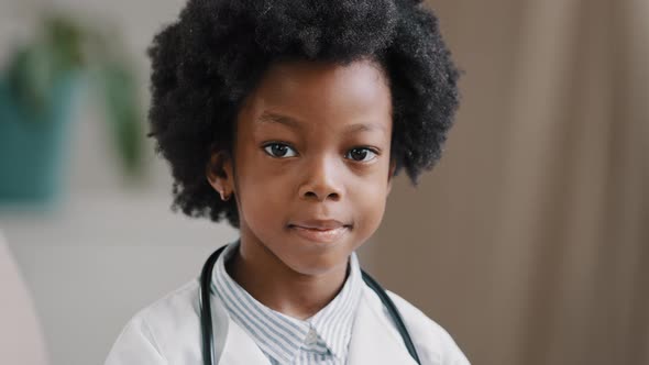 Cute Serious African American Kid Girl in Medical Clothes Dressed in White Coat Standing Indoors