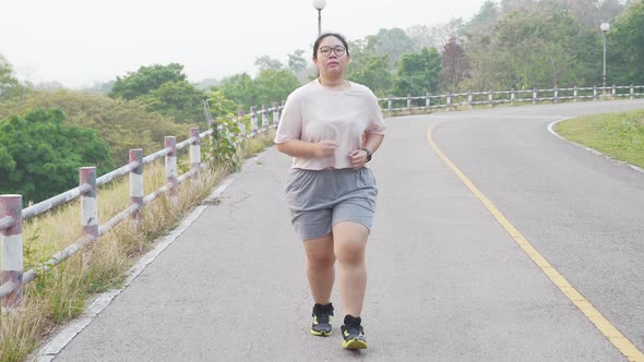 Fat Asian woman running, jogging outdoor at park.