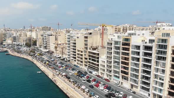 Aerial 4k footage flying towards a heavy trafficked area of a coastal city block of Sliema, Malta