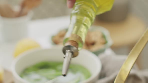 Crop lady adding olive oil to tasty pasta in pan