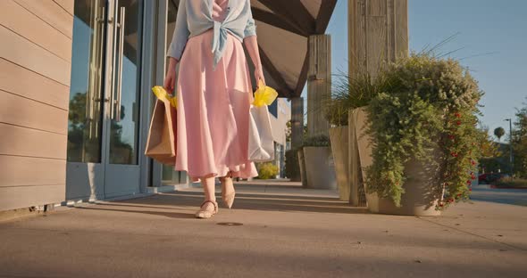 Woman in Pink Dress with Paper Bags Walking By Shopping Mall.  Slow Motion