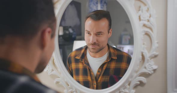 Smiling Man Giving Himself Wink in Front of Mirror