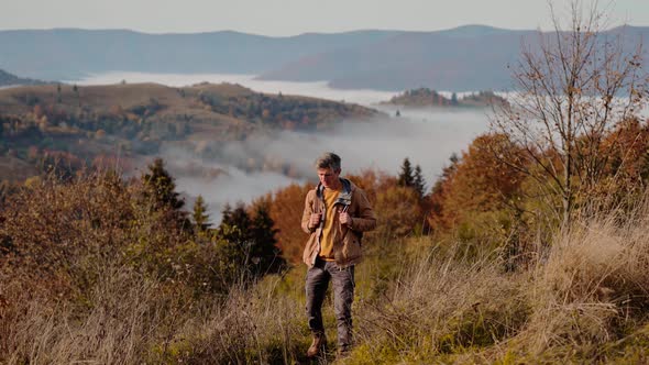 Male Hipster Adventourus Walks on Top of Mountain Pass at Early Morning Looking Around Enjoying