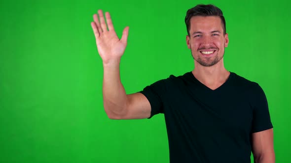 Young Handsome Caucasian Man Waves with Hand - Green Screen - Studio