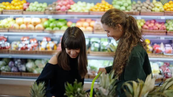 Two Caucasian Girls Choosing Bio Fruits  Grape in Supermarket Together