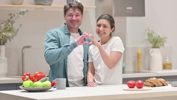 Mixed Race Couple Making Heart Shape By Hands While in Kitchen