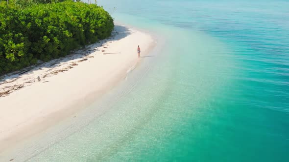 Aerial slow motion: lady walking on tropical beach at sunset, away from it all alt