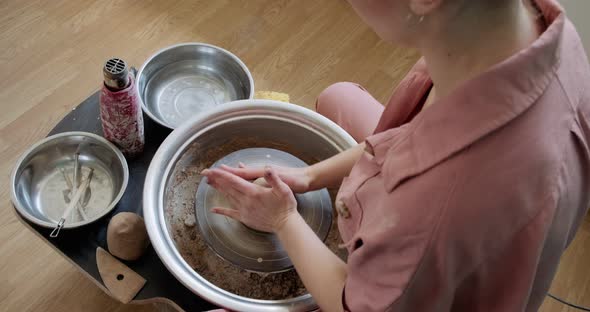 Female Potter Sitting and Makes a Cup on the Pottery Wheel. Woman Making Ceramic Item. Pottery