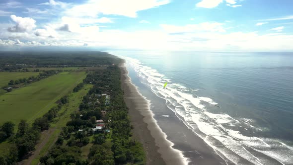 Aerial view of a paraglider flying over a beach on the coast of Costa Rica