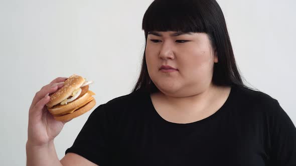 fat girl holding a bad hamburger and unhappy. fast food unhealthy food