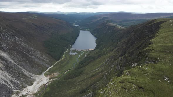 Overflying The Lush Green Forest And Mountain Range In Glendalough Overlooking The Upper Lake At Day
