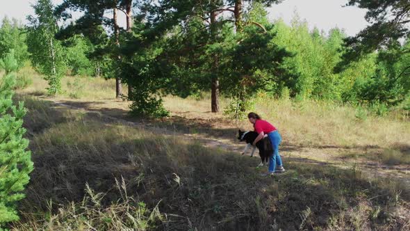 Young Plump Woman and Her Cute Dog Playing Outdoors Together  Aerial View