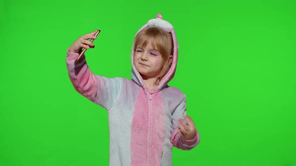 Child Girl in Unicorn Costume Pajamas Using Smartphone Kid Emotionally Makes Selfie on Mobile Phone