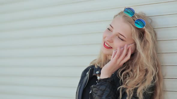 A Beautiful Young Blonde in a Leather Jacket and Wearing Glasses in the Style of John Lennon