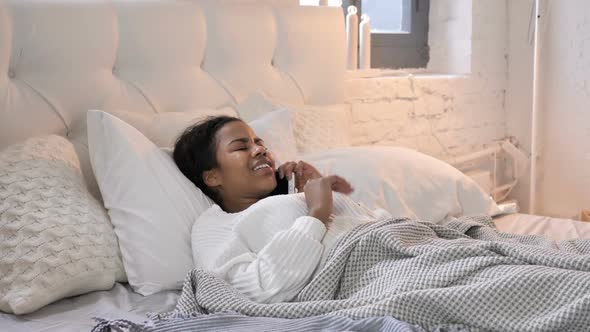 Young African Girl Talking on Phone While Laying in Bed